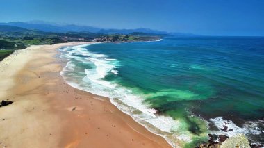 Nefes kesici insansız hava aracı görüntüleri güzel bir şekilde sakin dalgaları yakalıyor açık gökyüzünün altındaki altın kumlara hafifçe dokunuyor.