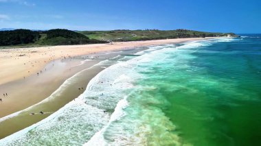 Büyüleyici bir hava perspektifi berrak turkuaz sular ve yumuşak altın kumlarla süslenmiş çarpıcı bir plajı gözler önüne seriyor.