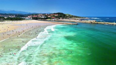 Çarpıcı turkuaz sular ve yumuşak kumlu kıyılar güzel güneşli bir günde keyifle sahile gidenlerle doludur.