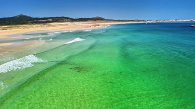 Berrak turkuaz suları ve altın kumları olan sakin bir plajın çarpıcı hava görüntülerini araştırın..