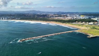 Nefes kesen bir hava manzarası, gün batımında güzel bir kıyı şeridine doğru hafif dalgalarla dalgalanan bir kıyı iskelesini gözler önüne seriyor.