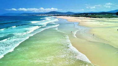 Yumuşak dalgaları, berrak suları ve dinginleşmek için mükemmel canlı gökyüzü olan çarpıcı bir sahil..