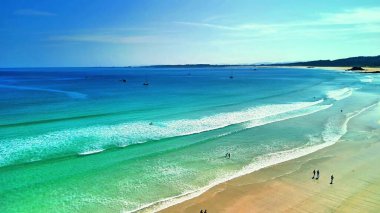 Sakin bir sahil manzarasının tadını çıkarın. Turkuaz suları ve yumuşak dalgaları var. Rahatlamak için mükemmel.