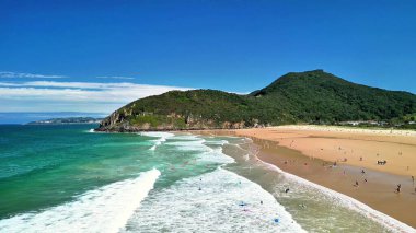 Nefes kesen plaj manzarası güzel dalgalar, altın kum ve gökyüzünün altındaki yemyeşil tepeler