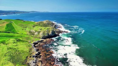 Nefes kesen kıyı manzaraları yemyeşil tepeler, engebeli kayalık kıyı şeridi ve canlı mavi okyanus dalgaları sergiliyor.