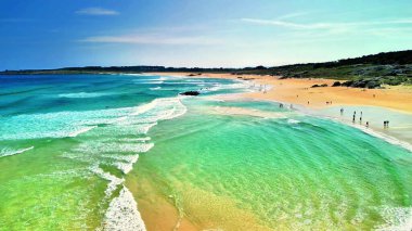 Kesinlikle nefes kesici bir plaj sahnesi çarpıcı turkuaz sular ve etraftaki yumuşak altın kumlar sergileniyor.
