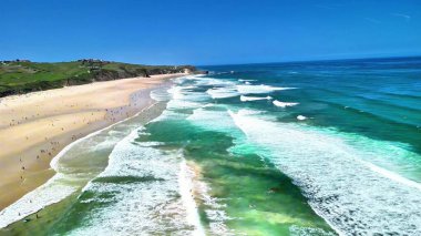 Bu çarpıcı manzarada dalgalar, kumlu plajlar ve güneşli gökyüzüyle dalgalı kıyı şeridini keşfedin.