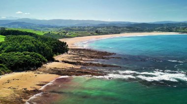 Berrak mavi suları, kayalık oluşumları ve yemyeşil yeşillikleri olan sakin bir sahil mükemmel bir kaçış sağlar.
