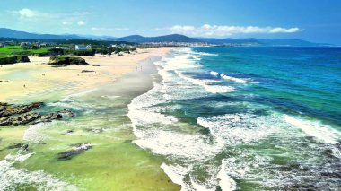 Bu nefes kesici hava çekimi, canlı turkuaz su ve parıldayan altın kumlarla çarpıcı bir sahili yakalar.