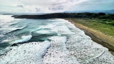 Güzel bir sahil manzarasında sakin bir plaja çarpan dalgaların gerçekten çarpıcı manzarasının tadını çıkarın.
