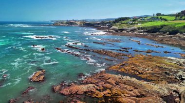 Engebeli kayaların yanında berrak turkuaz suların sergilendiği çarpıcı kıyı manzarasını deneyin.