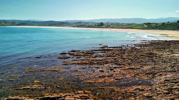 Bu sakin bir sahilin nefes kesici bir görüntüsü, engebeli kayalar ve dalgaların yanında pürüzsüz kumlu kıyılar var.