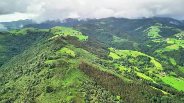 Sersemletici hava görüntüsü güzel yeşil tepeleri ve vadileri sergiliyor dramatik bulutlu gökyüzünün altında