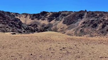 Kayalık tepeler ve güzel berrak mavi gökyüzü ile karakterize edilmiş kurak ve kuru bir manzaranın nefes kesici manzarasına bakın.