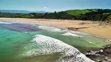 Güzel bir sahilin büyüleyici bir görüntüsü. Hafif dalgalar ve güneşli günün tadını çıkaran güneşli bir sahil..