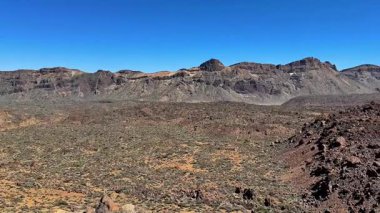 Nefes kesen kayalık bir çöl manzarasını keşfedin göz kamaştırıcı dağlar tarafından çerçevelenmiş canlı mavi gökyüzünün altında
