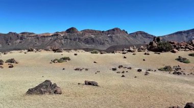 Çarpıcı manzara, berrak mavi gökyüzüne karşı engebeli kayaları barındıran engin çöl manzarasını ön plana çıkarıyor.