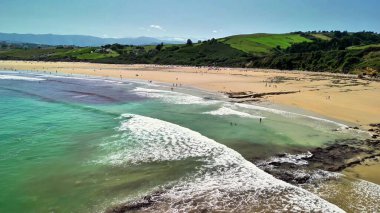 Güzel bir sahilin büyüleyici bir görüntüsü. Hafif dalgalar ve güneşli günün tadını çıkaran güneşli bir sahil..