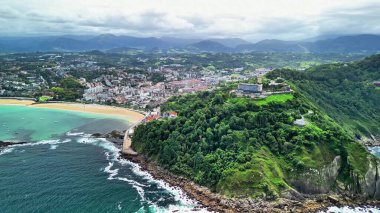 Canlı yeşil tepeler ve sakin suların bulunduğu nefes kesici bir kıyı kasabasının nefes kesici hava manzarası.