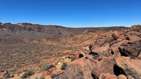 Kayalık çöl manzarasının nefes kesici manzarası açık mavi bir gökyüzü ve uçsuz bucaksız bir ufuk altında uzanır.