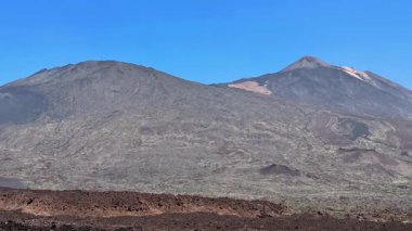 Volkanik bir dağ sırasının nefes kesen manzarası kayalık arazisini kıtır mavi gökyüzüyle çevreler.