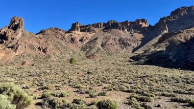 Berrak mavi gökyüzünün altında canlı ve renkli bir çölün nefes kesici güzellikteki kayalık manzarasını keşfedin.