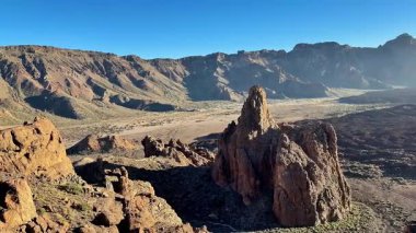 Kayalık dağların ve jeolojik oluşumların çarpıcı manzarası berrak mavi gökyüzünün altında güzel bir şekilde yatıyor.