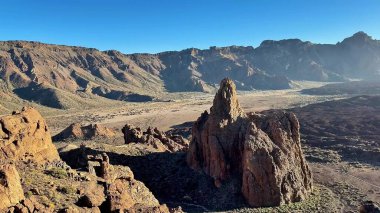 Kayalık dağların ve jeolojik oluşumların çarpıcı manzarası berrak mavi gökyüzünün altında güzel bir şekilde yatıyor.