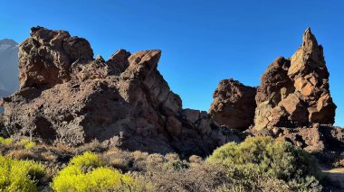 Gelin ve bulutlar tarafından lekelenmemiş canlı, berrak mavi gökyüzüne karşı oluşturulan resimsel çöl kaya oluşumlarını keşfedin.