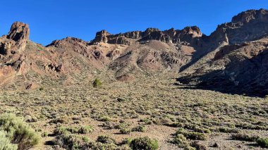 Berrak mavi gökyüzünün altında canlı ve renkli bir çölün nefes kesici güzellikteki kayalık manzarasını keşfedin.