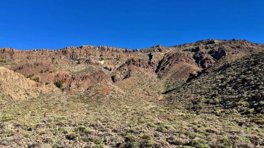 Parlak mavi gökyüzünün altındaki kayalık araziyi gösteren kesinlikle çarpıcı ve güzel bir manzara.