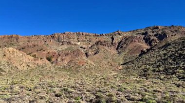 Parlak mavi gökyüzünün altındaki kayalık araziyi gösteren kesinlikle çarpıcı ve güzel bir manzara.