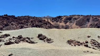 Geniş kayalık bir arazinin nefes kesici manzarası güzel, açık mavi bir gökyüzü altında, doğal güzellikler sergiliyor.