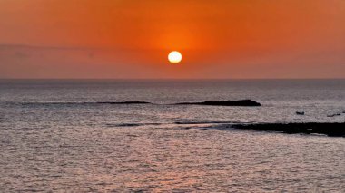 Nefes kesen bir günbatımı okyanusun üzerine çarpıcı bir ışık saçıyor, canlı renkler ve dingin bir sükunet sergiliyor.