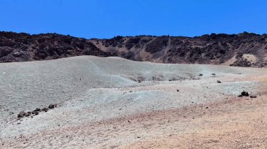 Kurak çöl arazisinin büyüleyici manzarası güzel bir şekilde renkli dokularını ve oluşumlarını gözler önüne seriyor.