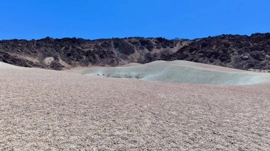 Benzersiz bir çöl manzarasının nefes kesici ve çarpıcı görüntüsü ince kum tepelerini ve çarpıcı volkanik kayaları gözler önüne seriyor.