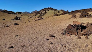 Kayalık arazi, engebeli oluşumlar ve çorak tepeler içeren kurak bir arazinin çarpıcı panoramik manzarası.