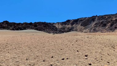 Çorak ve engebeli bir arazinin çarpıcı güzellikte manzarası altında kayalık bir arazi var.