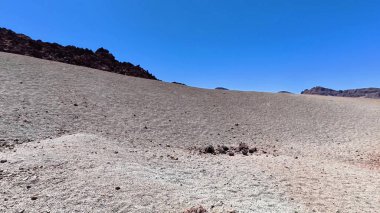 Kurak bir arazide kuru toprak ve kayalık tepeler sergileniyor. Güneş ışığıyla aydınlatılmış, doğa projeleri için ideal.