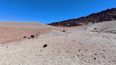 Parlak mavi gökyüzünün altında engebeli kayalarla süslenmiş uçsuz bucaksız çorak bir arazinin gerçekten çarpıcı manzarasına tanık olun.