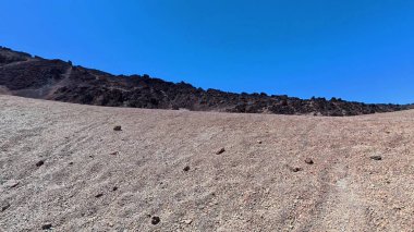 Açık mavi gökyüzünün altında kayalık tepelerin bulunduğu çarpıcı, çorak bir manzara. Açık hava temaları için mükemmel..