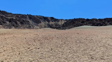 Uçsuz bucaksız kurak bir arazide engebeli kayalık tepelerin altında nefes kesen parlak mavi gökyüzünün altında