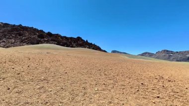 Berrak ve engebeli bir arazinin göz alıcı güzellikte manzarası berrak mavi bir gökyüzünün altında kayalık bir arazi barındırıyor.