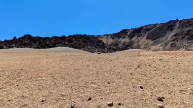 Çorak ve engebeli bir arazinin çarpıcı güzellikte manzarası altında kayalık bir arazi var.