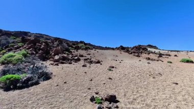 Nefis bir çöl manzarası sergiliyor. Parlak mavi gökyüzüne karşı kayalık dokular sergiliyor.