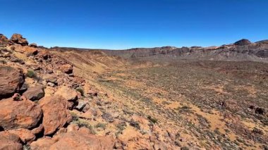 Sersemletici kaya oluşumları ve açık mavi gökyüzünün altındaki yemyeşil bitki örtüsüyle nefes kesici çöl manzaralarını keşfedin.