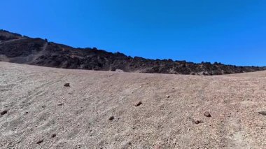 Açık mavi gökyüzünün altında kayalık tepelerin bulunduğu çarpıcı, çorak bir manzara. Açık hava temaları için mükemmel..