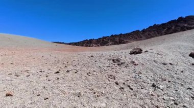 Uçsuz bucaksız ve kurak bir arazinin nefes kesici manzarası, berrak, mavi gökyüzünün altındaki engebeli kayalık araziyi gözler önüne seriyor.