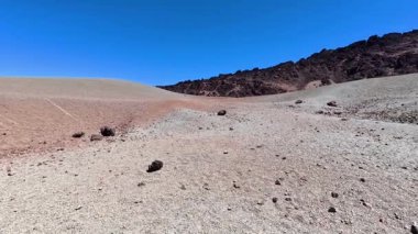 Parlak mavi gökyüzünün altında engebeli kayalarla süslenmiş uçsuz bucaksız çorak bir arazinin gerçekten çarpıcı manzarasına tanık olun.