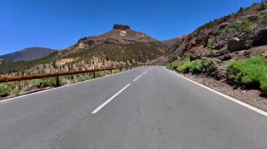 Dolambaçlı bir yol berrak gökyüzünün altında sersemletici dağların arasında dolaşır sükunet ve macerayı somutlaştırır.